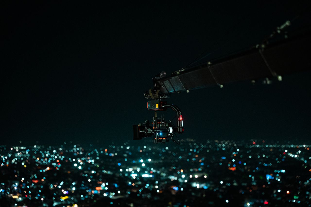 A heavy-lift cinema gimbal rig flying over a city at night